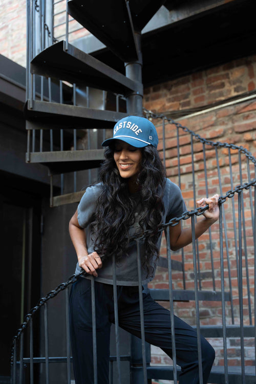 Woman on stairs outside in blue custom made hat with EASTSIDE text