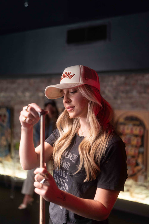 Woman playing pool in custom made trucker hat with PHOENIX text