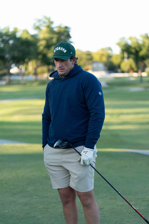 Man on a golf course with a custom made green hat with upside down text MAGNOLIA